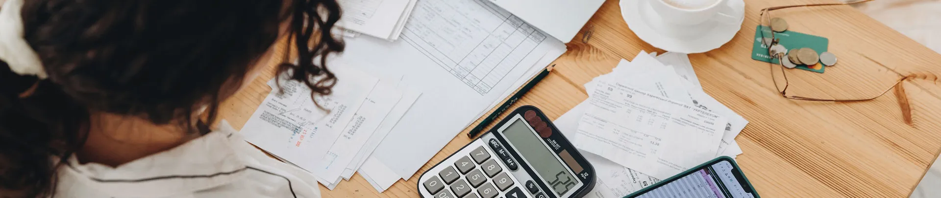 Bovenaanzicht van een vrouw die thuis in de keuken werkt met financiële papieren