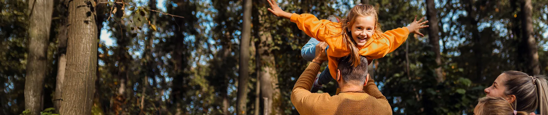Een lachend gezin van vier geniet van de natuur tijdens een wandeling in het bos.